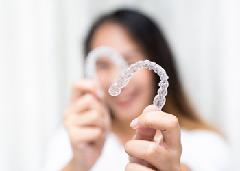 Patient smiling while holding clear aligner