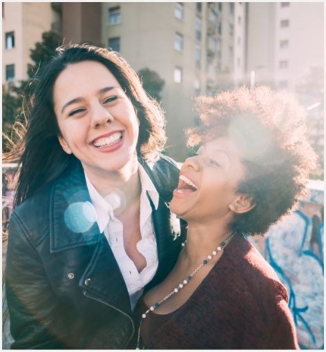 Two women laughing outdoors after cosmetic dentistry in Hayward