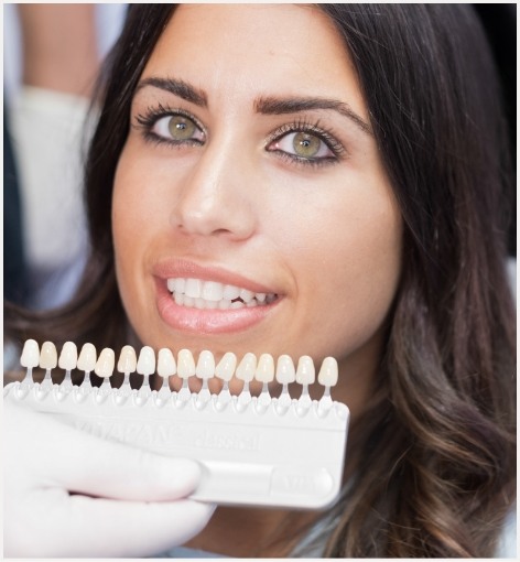 Woman smiling next to row of dental veneers