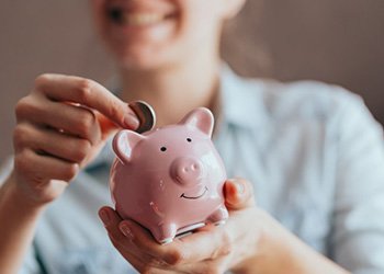 Close up of woman inserting a coin into a piggy bank