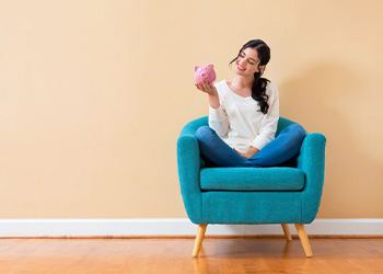 Woman sitting in a comfy chair and holding a piggy bank