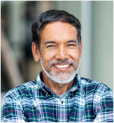 Man in blue plaid shirt smiling with dental implants in Hayward