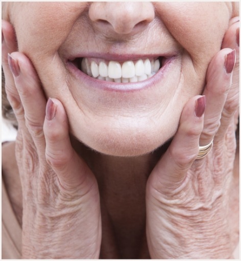 Close up of smiling senior woman touching her face