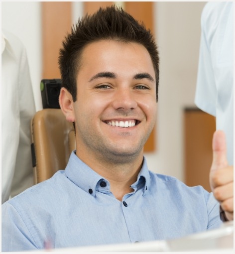 Smiling man giving thumbs up in dental chair