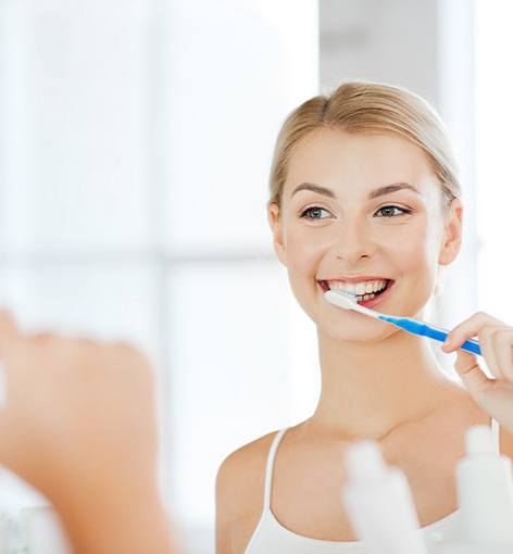 Woman looking in mirror and brushing her teeth