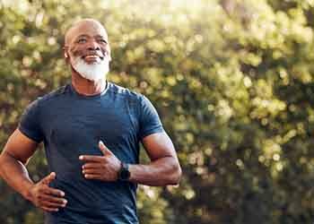 an older man jogging outside and smiling