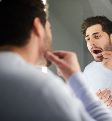 Man looking at his teeth in the mirror