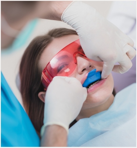 Young woman in dental chair with fluoride trays over her teeth