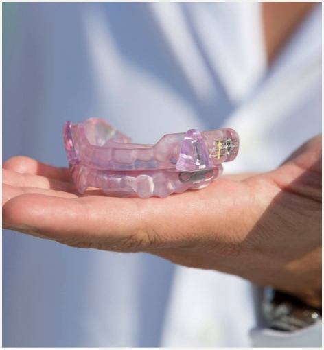 Hand holding a light purple oral appliance